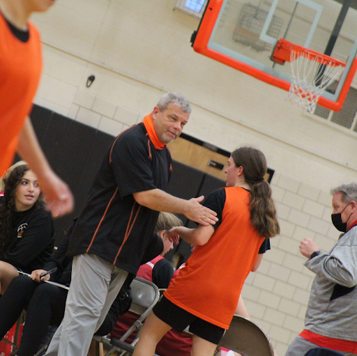 Recently appointed girls varsity basketball coach, Dave Arnold, pats Amina Ferris, point guard player,
on the back during the DHS vs. Stevenson scrimmage game on Nov. 17, 2021. Junior power
forward player Celine Bazzi said that it took the team some time to get comfortable playing together strongly. “In the beginning of the scrimmage it was hard for us to adjust to how we were
all playing together because it was our first couple of games. I feel like we adjusted more, we got more comfortable with each other, so we were able to beat teams that we struggled to beat
before in the past,” Bazzi said.